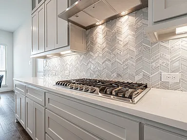 Gas cooktop with chevron tile backsplash detail in kitchen remodel Allen TX by UHS Remodeling