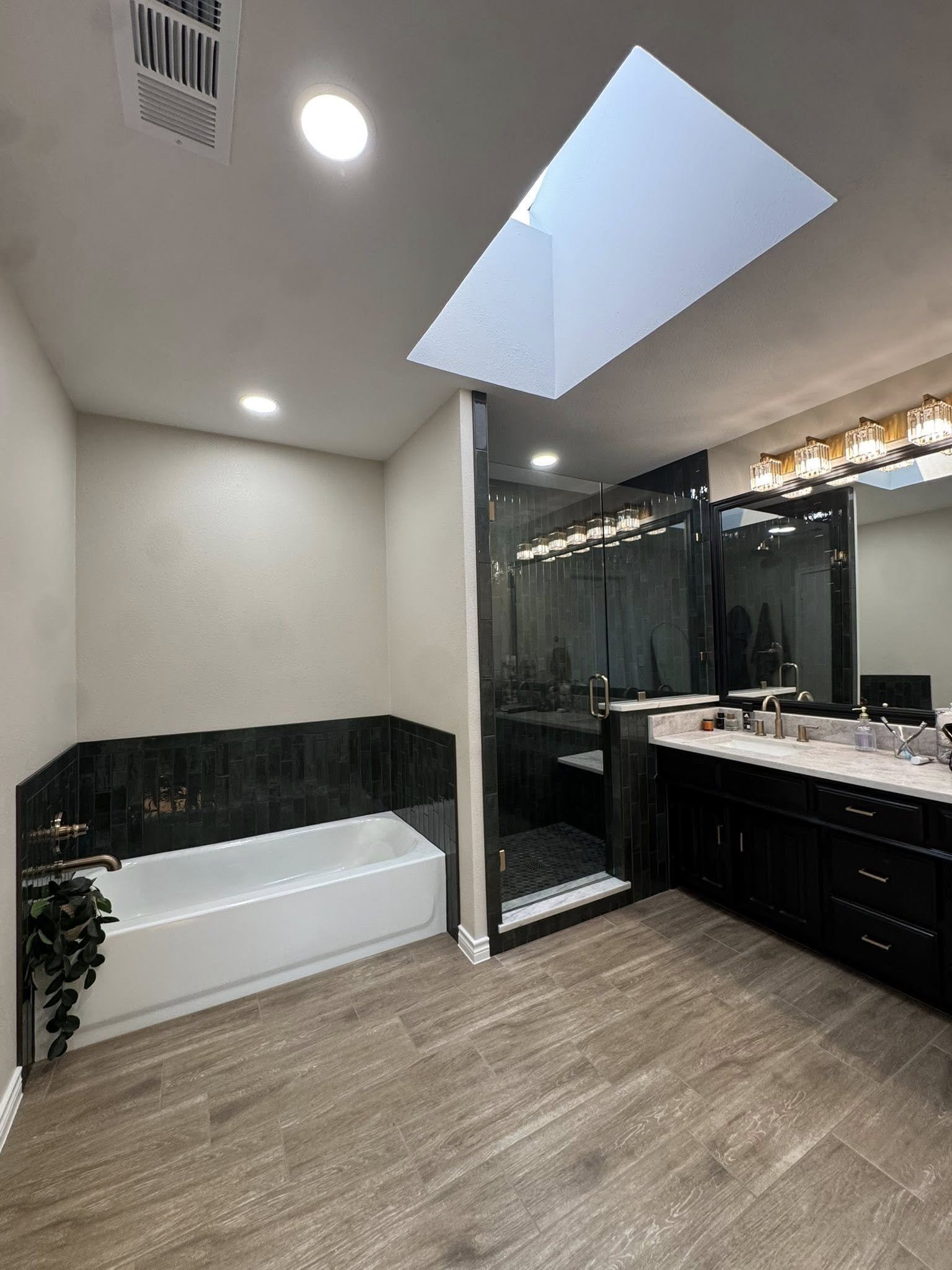 Allen, TX bathroom remodel with a skylight, soaking tub and dark tile shower by UHS Remodeling