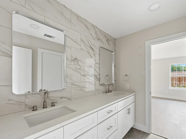 Luxury bathroom remodel in Richardson TX with dual vanity and marble accent wall by UHS Remodeling