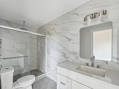 Walk-in shower with marble tile in Richardson TX bathroom remodel by UHS Remodeling