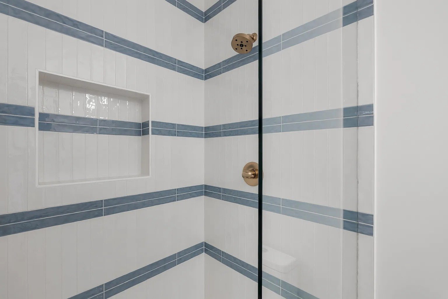 Kids walk-in shower with white and blue stripe tile in full home remodel Dallas TX by UHS Remodeling