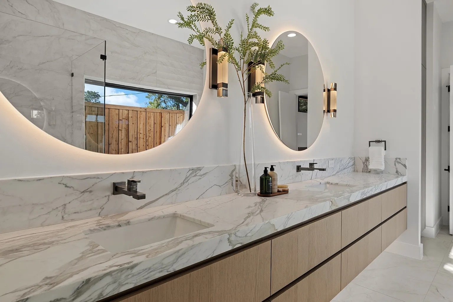 Primary bathroom with LED oval mirrors and marble vanity in full home remodel Dallas TX by UHS Remodeling