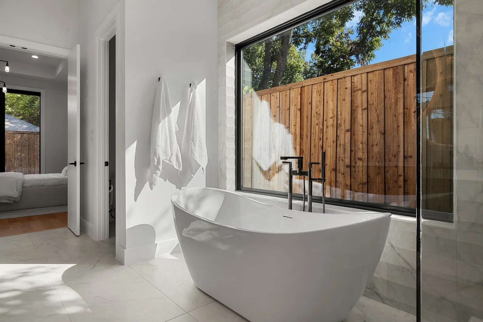 Freestanding soaking tub with window view in master bathroom remodel Dallas TX by UHS Remodeling