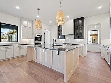 Open concept white kitchen with large island in full home remodel Dallas TX by UHS Remodeling