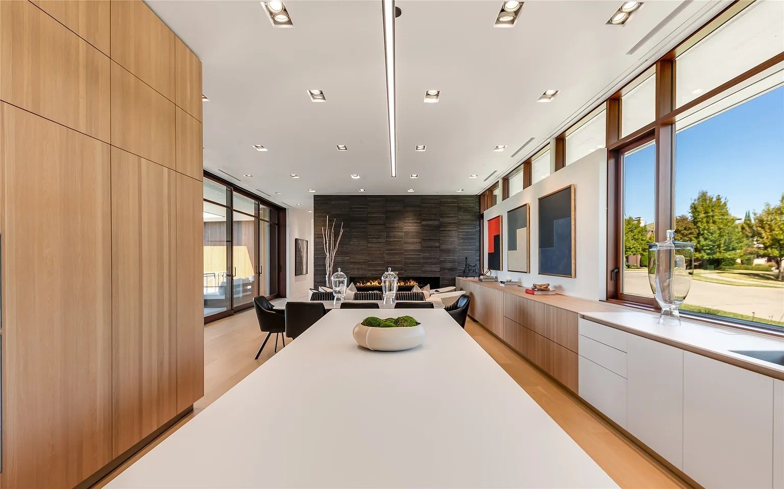 Minimalist luxury kitchen island facing stone fireplace wall in Dallas TX by UHS Remodeling