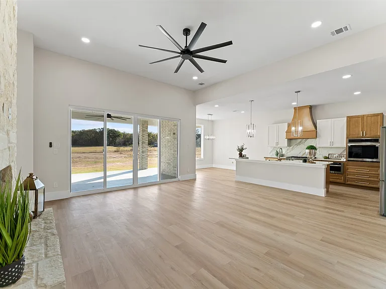 Great room with custom wood range hood and open kitchen in builder home kitchen upgrade Frisco TX by UHS Remodeling