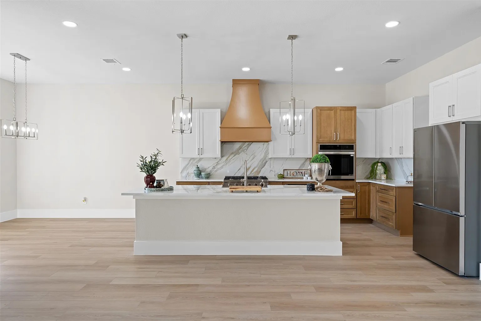 Two-tone kitchen with custom wood range hood and island in builder home upgrade Frisco TX by UHS Remodeling