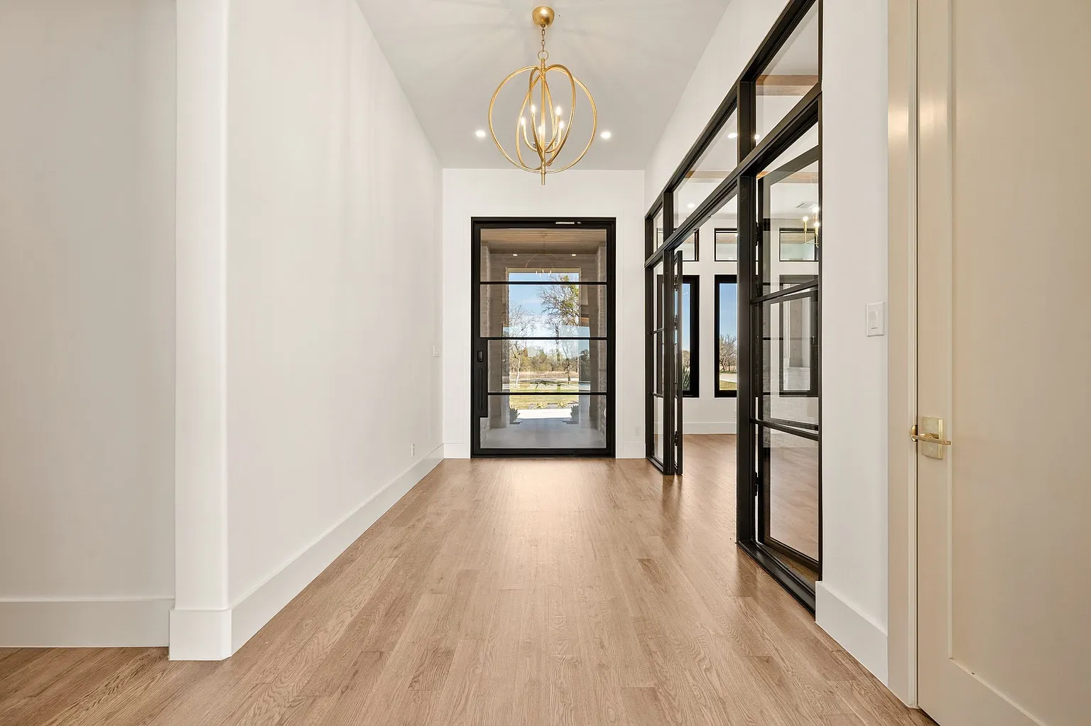 Grand entry hallway with steel glass doors and brass chandelier in full home renovation Frisco TX by UHS Remodeling