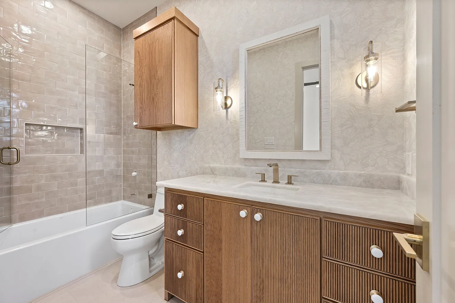 Guest bathroom with fluted wood vanity and subway tile tub surround in full home renovation Frisco TX by UHS Remodeling