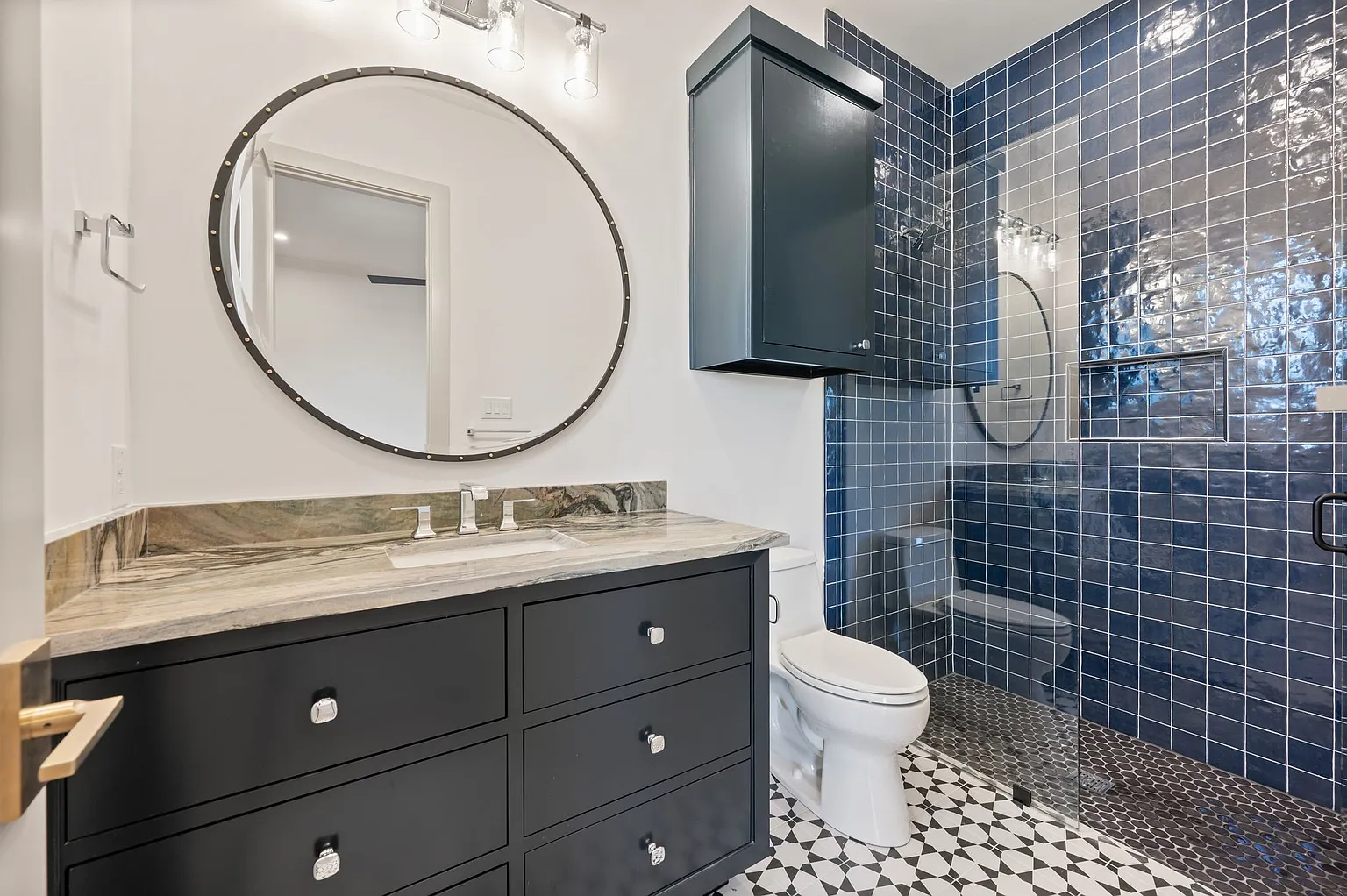 Kids bathroom with navy blue tile walls and round mirror in full home renovation Frisco TX by UHS Remodeling