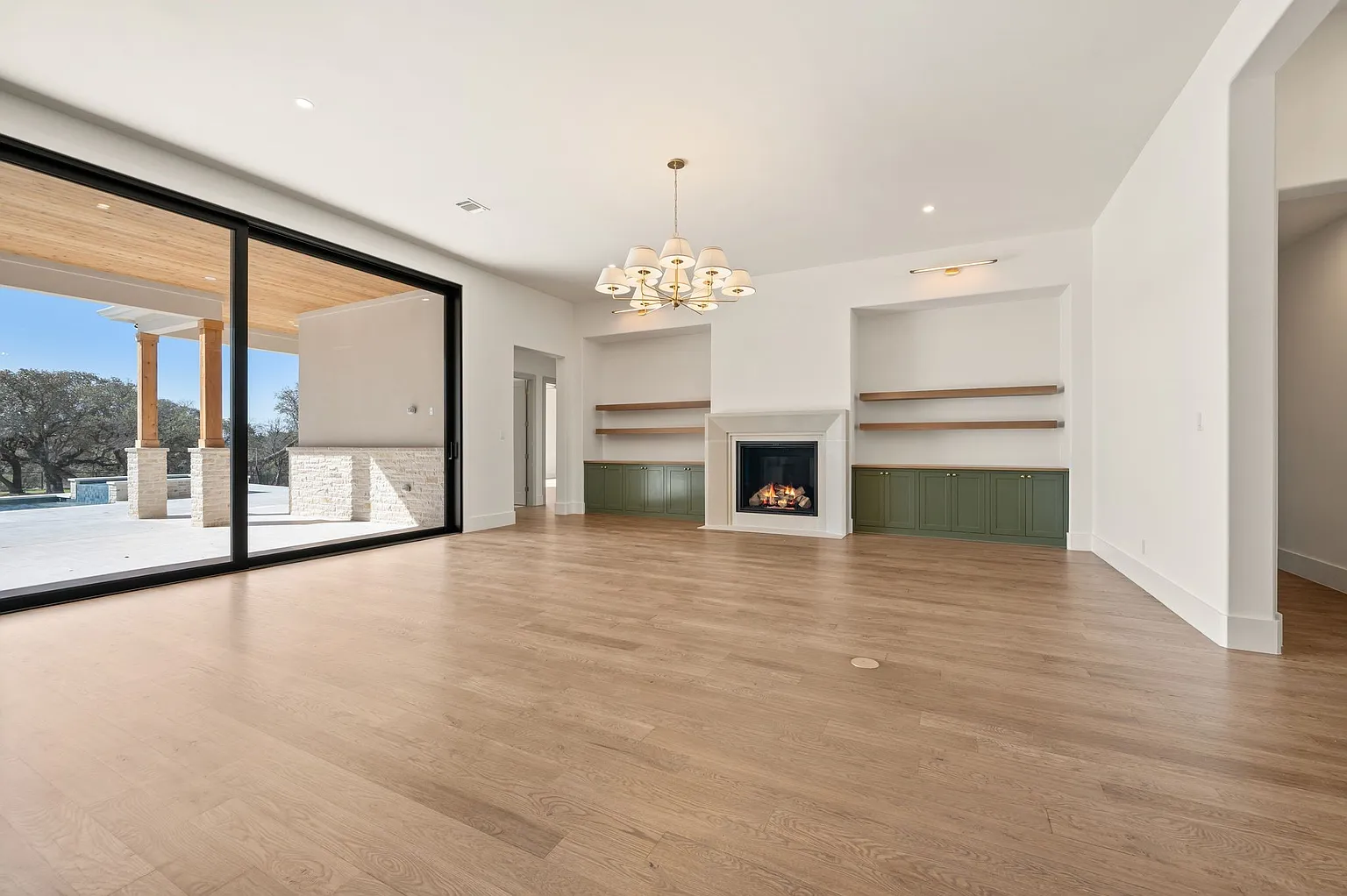 Living room with fireplace, floating shelves, and pool view in full home renovation Frisco TX by UHS Remodeling