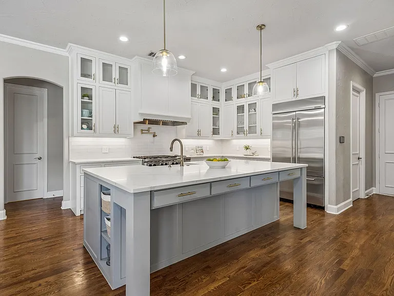 Transitional kitchen remodel in Garland TX with white shaker cabinets blue-gray island and gold hardware by UHS Remodeling
