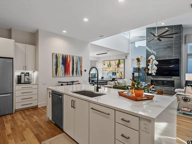 Modern open-plan kitchen remodel in Highland Park TX with white flat-panel cabinets and quartz island by UHS Remodeling