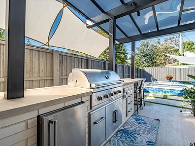Outdoor kitchen with built-in grill and pool area in Highland Park TX by UHS Remodeling