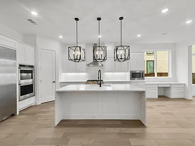 White kitchen with island and pendant lights by UHS Remodeling
