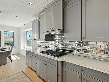Kitchen close-up with mirrored backsplash and gas cooktop in Little Elm TX by UHS Remodeling