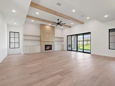 Living room addition with exposed wood beams and fireplace in Plano TX by UHS Remodeling