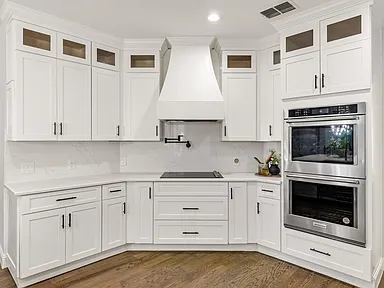 White kitchen cabinets with custom range hood and quartz countertops in Plano TX remodel