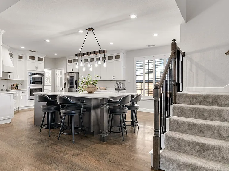 Open-concept kitchen remodel in Plano TX with white shaker cabinets and dark contrast island by UHS Remodeling