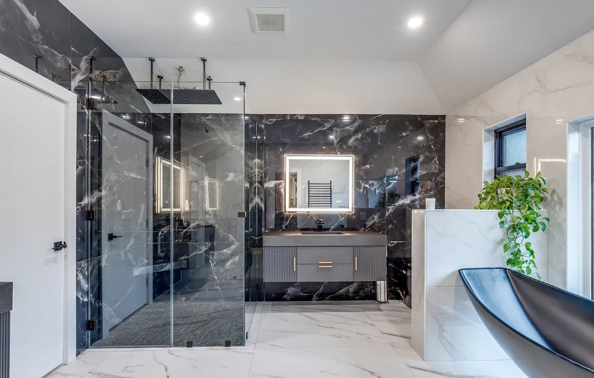 Luxury primary bathroom with black marble walls and black freestanding tub in Plano TX by UHS Remodeling