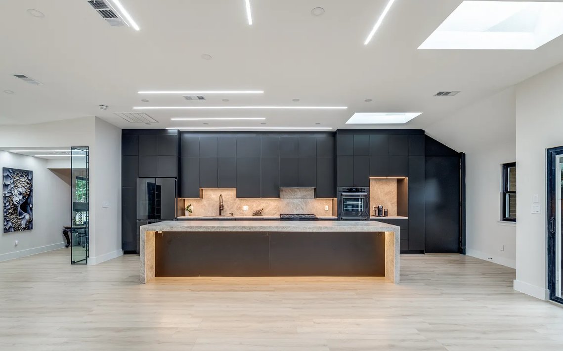 Modern black kitchen with marble waterfall island and LED ceiling lights in Plano TX by UHS Remodeling