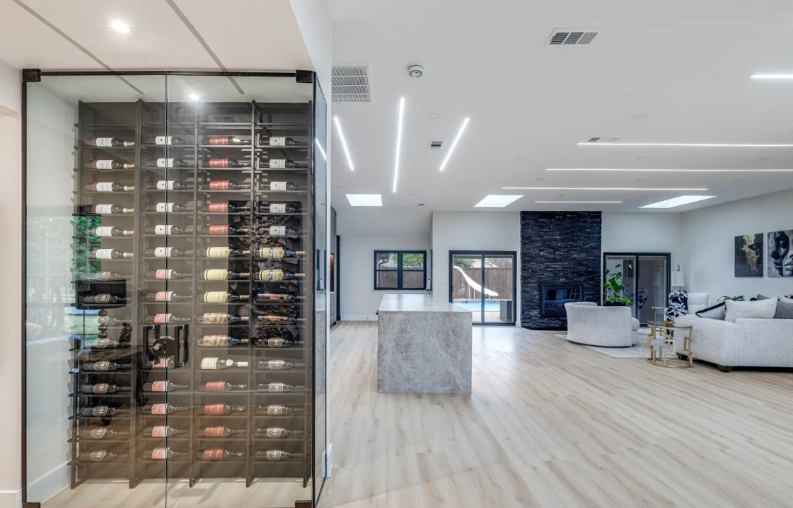 Glass wine cellar feature in open living area of modern kitchen remodel Plano TX by UHS Remodeling