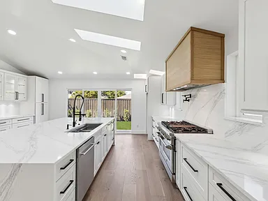 Remodeled galley kitchen with marble waterfall island in full home renovation Richardson TX by UHS Remodeling