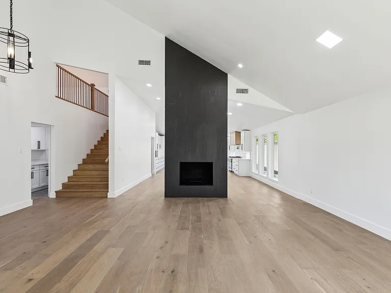 Double-height great room with black fireplace feature wall after 1970s home renovation Richardson TX by UHS Remodeling