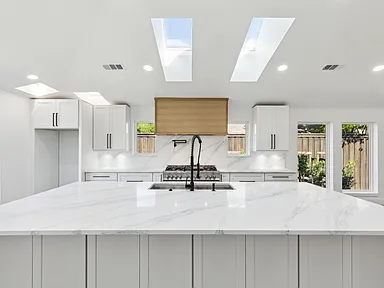 Remodeled kitchen with double skylights and waterfall marble island in full home renovation Richardson TX by UHS Remodeling