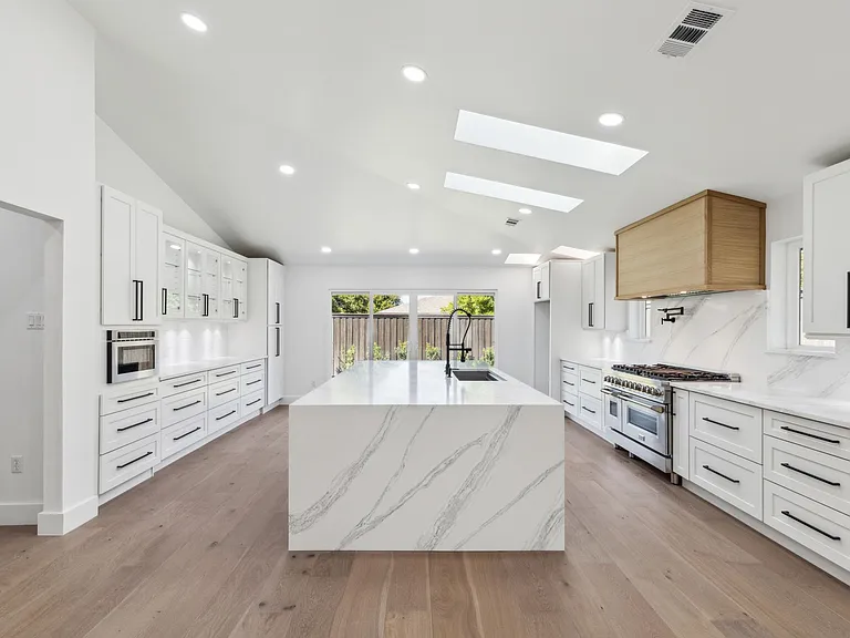 Luxury kitchen remodel with waterfall island and professional range in 1970s home renovation Richardson TX by UHS Remodeling