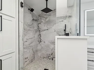 Walk-in shower with book-matched marble slab walls in 1970s home renovation Richardson TX by UHS Remodeling
