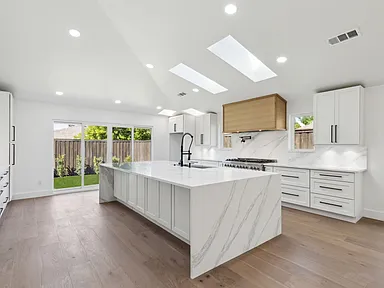 Open concept kitchen with marble island and skylights in full home renovation Richardson TX by UHS Remodeling
