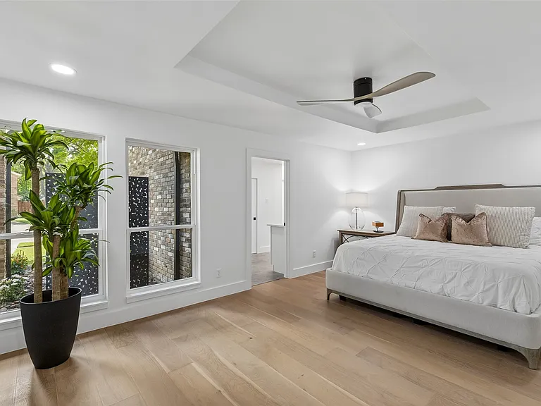 Primary bedroom with tray ceiling and wide plank floors in 1970s home renovation Richardson TX by UHS Remodeling