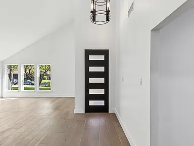 Modern vaulted entryway with black contemporary door in 1970s home renovation Richardson TX by UHS Remodeling