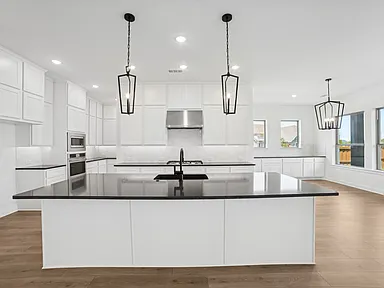 Modern kitchen remodel in Rockwall TX with white flat-panel cabinets black quartz island and lantern pendants by UHS Remodeling