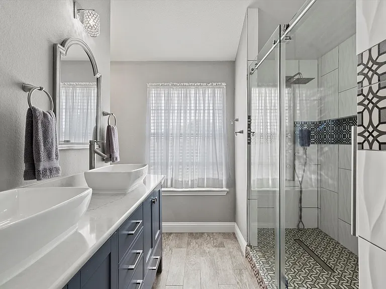 Master bathroom wider view with glass shower and patterned tile in Rowlett TX