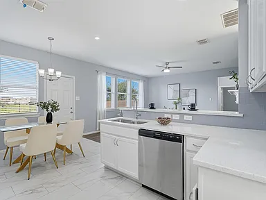 Open-concept white kitchen remodel in Sachse TX with island and dining area by UHS Remodeling
