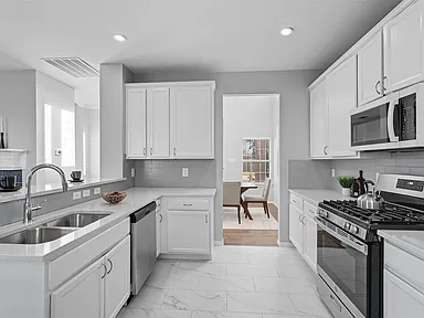 Galley kitchen with white shaker cabinets and stainless appliances in Sachse TX by UHS Remodeling