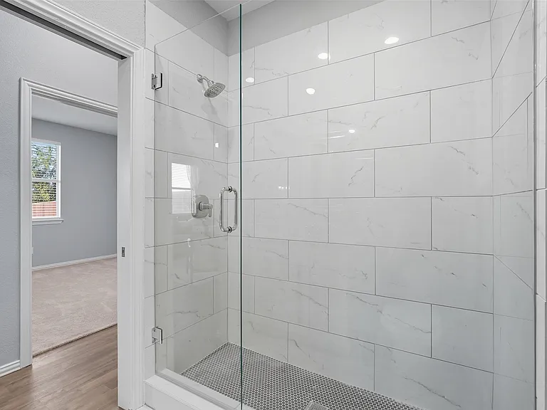 Walk-in shower with marble-look tile and frameless glass in Sachse TX bathroom remodel