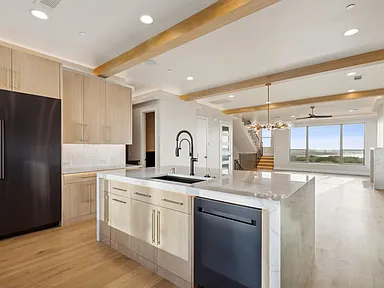 High-end kitchen remodel in The Colony TX with two-tone cabinets waterfall island and exposed beams by UHS Remodeling