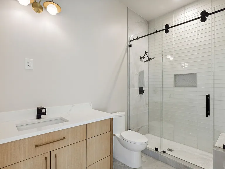 Guest bathroom with light wood vanity and barn-door shower in The Colony TX by UHS Remodeling