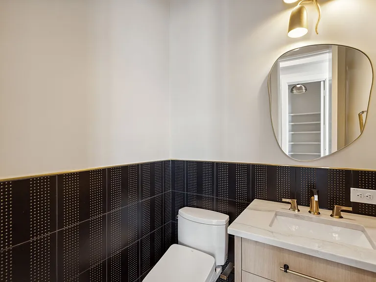 Luxury powder room with dark patterned tile and gold mirror in The Colony TX by UHS Remodeling
