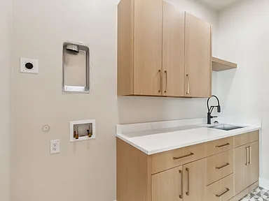 Laundry room with light wood cabinets and patterned floor in The Colony TX by UHS Remodeling