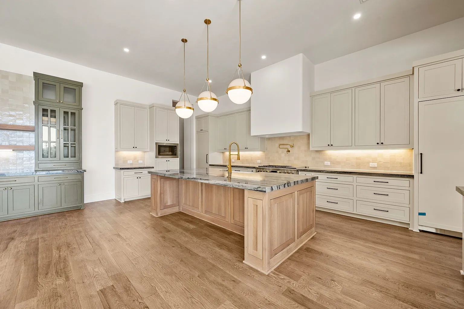 Two-tone kitchen with sage green Shaker cabinets, a white oak island, and glass-front upper cabinets in Allen TX