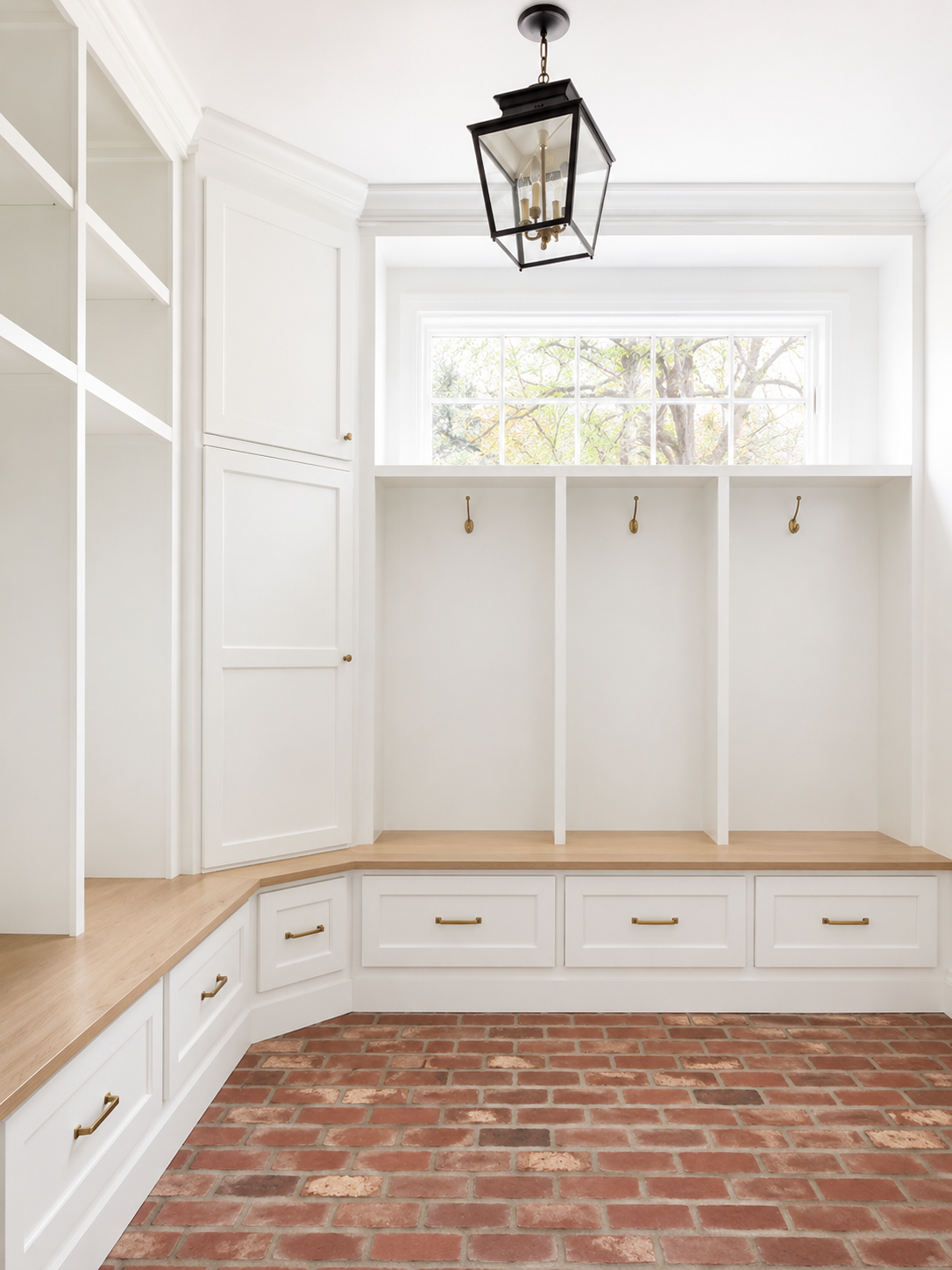 White mudroom with a bench, cubbies, hooks and brick floor in DFW