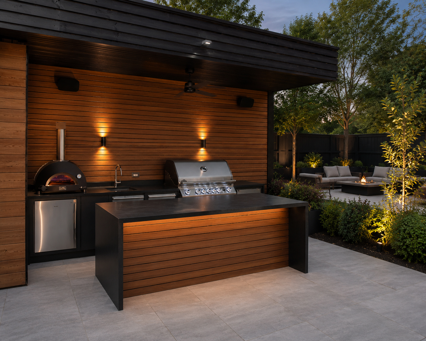 Modern wood-paneled outdoor kitchen with a built-in grill, a pizza oven, and warm evening lighting