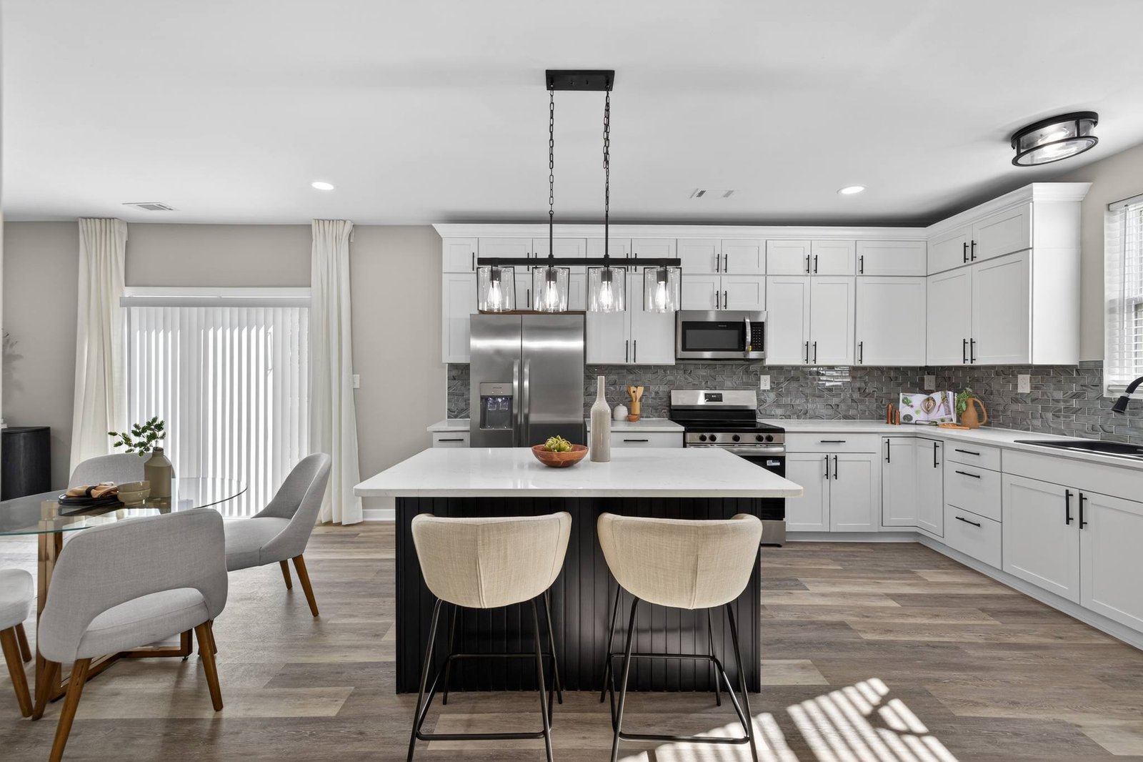 Open kitchen with white shaker cabinets and a dark island in a Frisco, TX renovation by UHS Remodeling