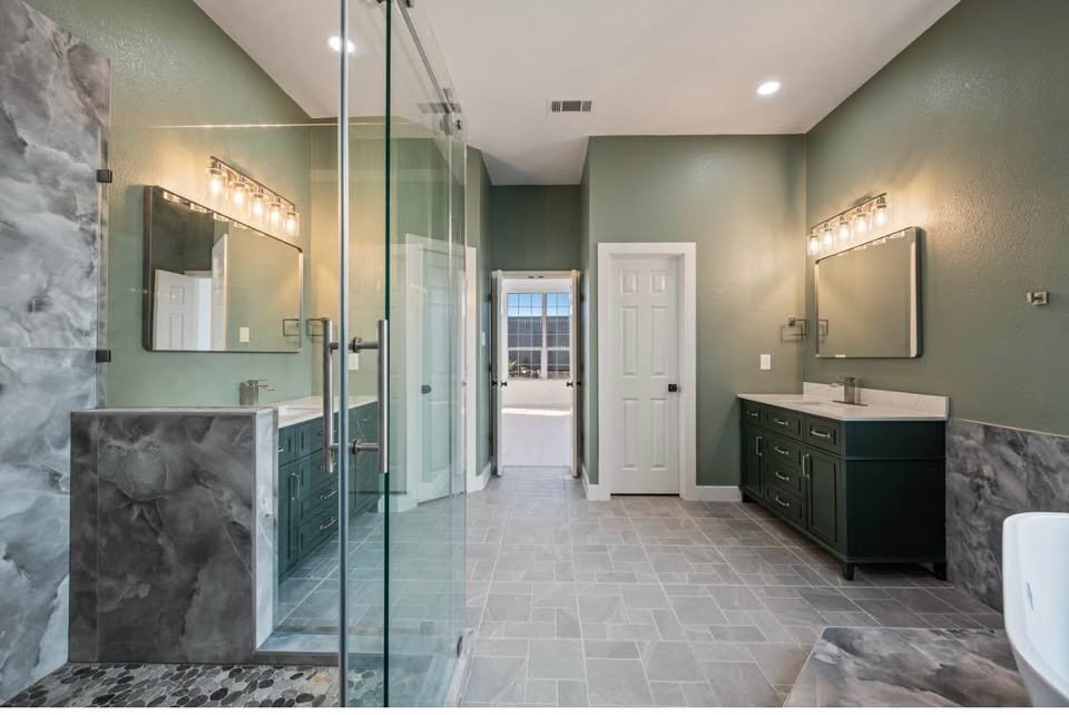 Primary bathroom with a glass walk-in shower, dual vanities, and sage walls in a Frisco, TX interior remodel by UHS Remodeling