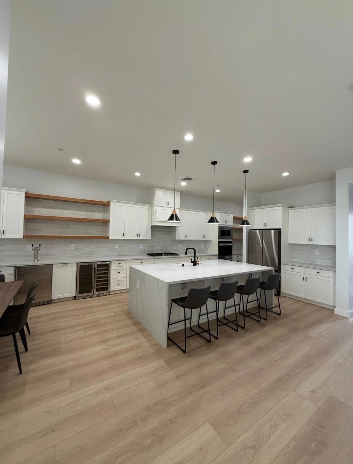 Bright white kitchen with a marble waterfall island, open shelving, and pendant lighting in a Richardson, TX interior remodel by UHS Remodeling