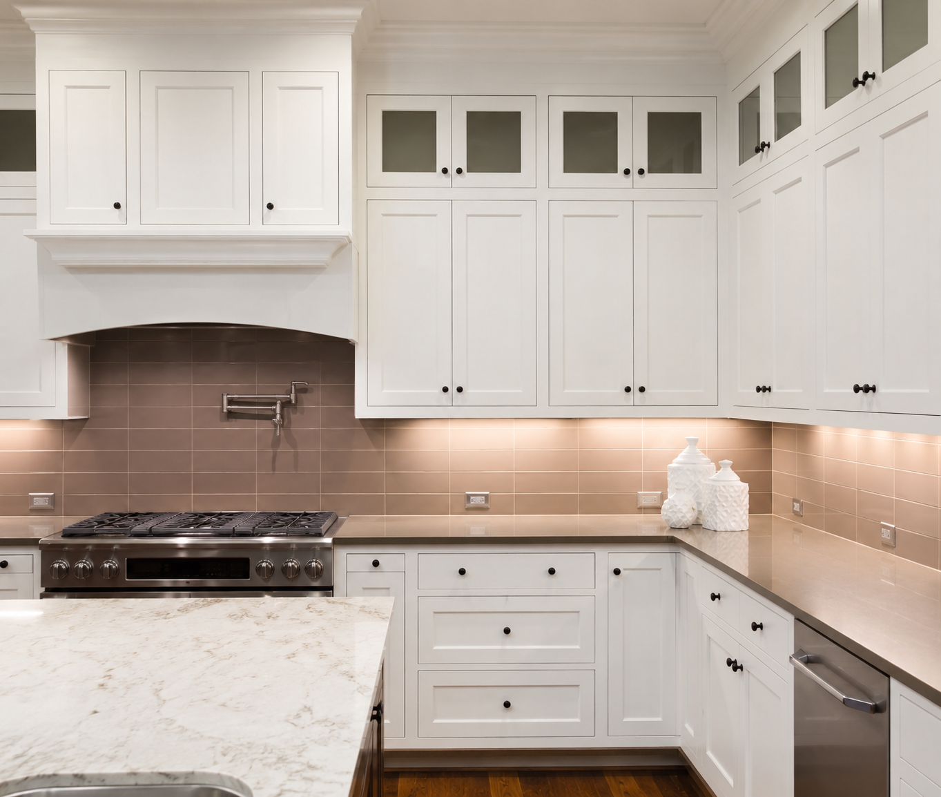 White shaker kitchen cabinets with a marble island and subway tile